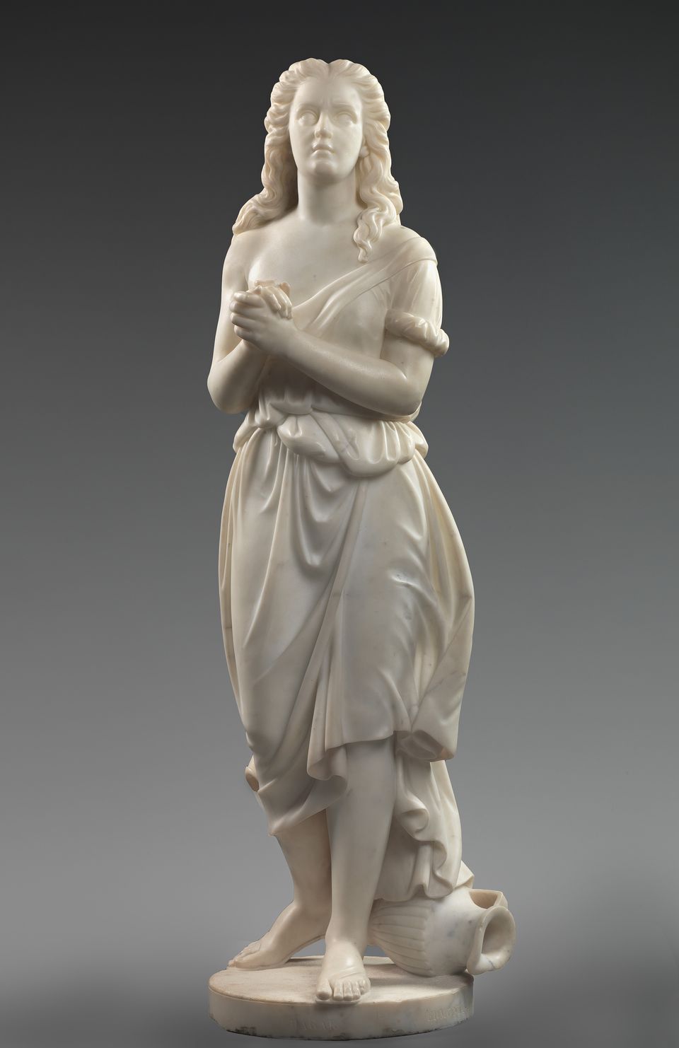 Marble statue depicting the biblical figure Hagar, standing with a water pitcher at her feet and her arms crossed in front of her.