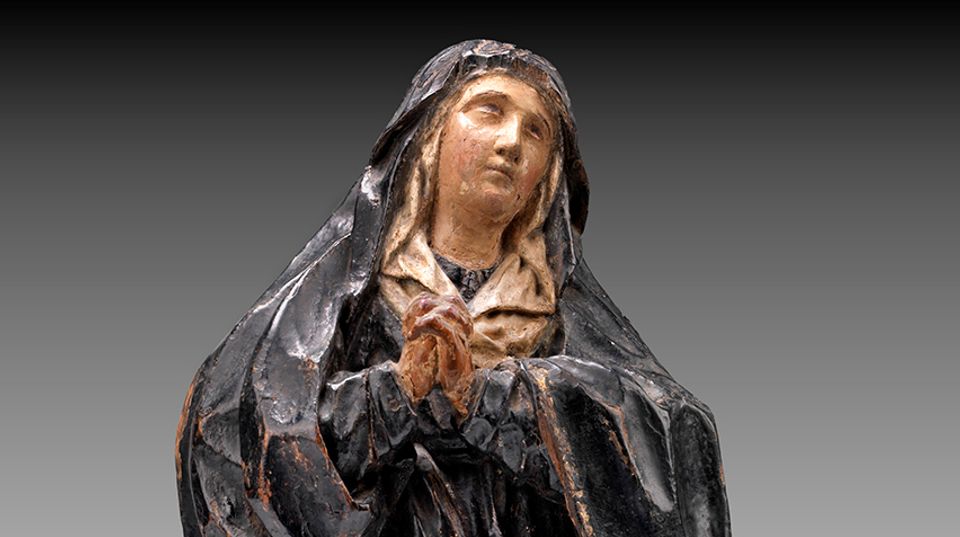 Detail of a wooden carving of Nuestra Señora de los Dolores (Our Lady of Sorrows). She  is looking up and away with her hands clasped in prayer.
