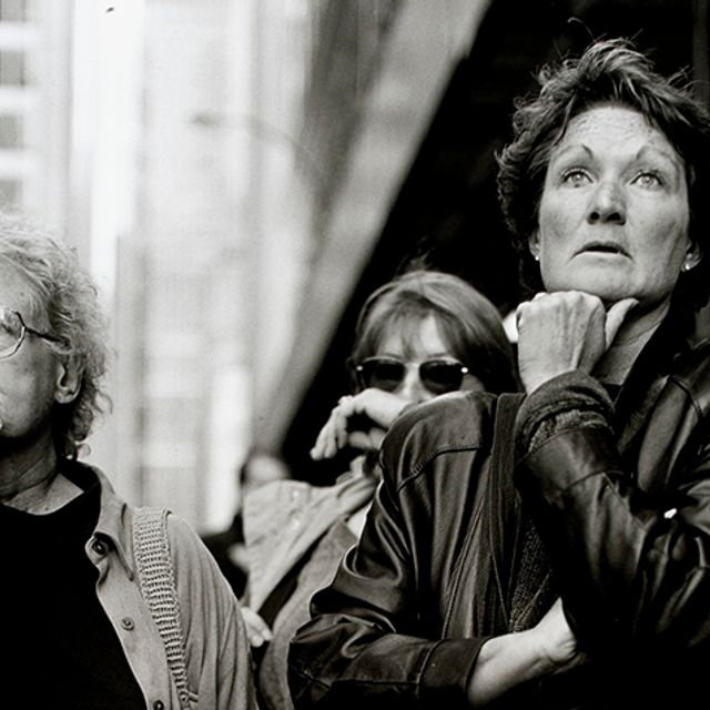 A black and white photograph of three women looking in the near distance with shocked looks on their faces