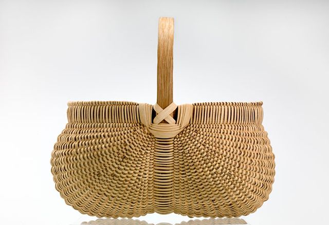 A basket with two circular sides that come together in the middle and are connected to a handle.