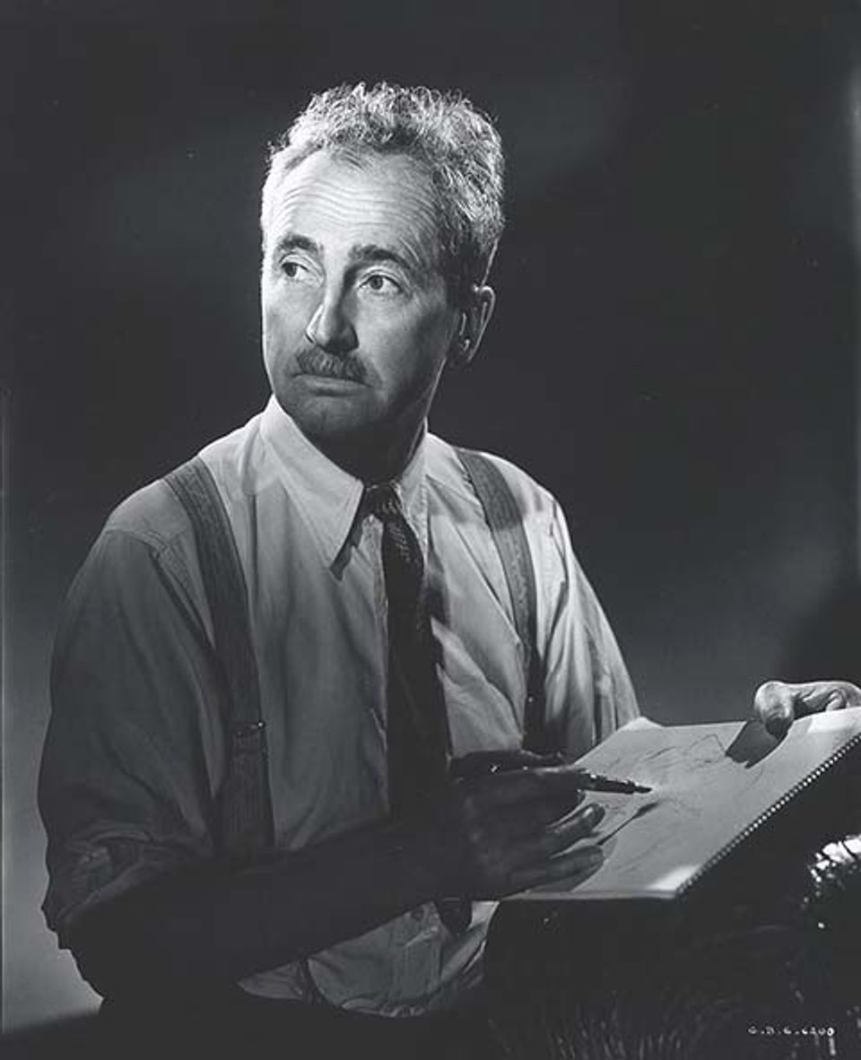 A photograph of a man sitting with pen and paper in hand.