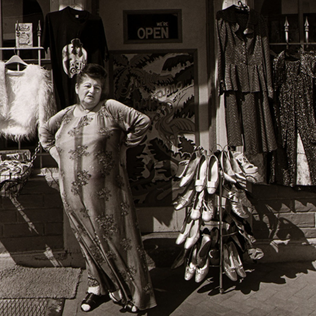 A black and white photograph of Edith Massey standing in front of her store.