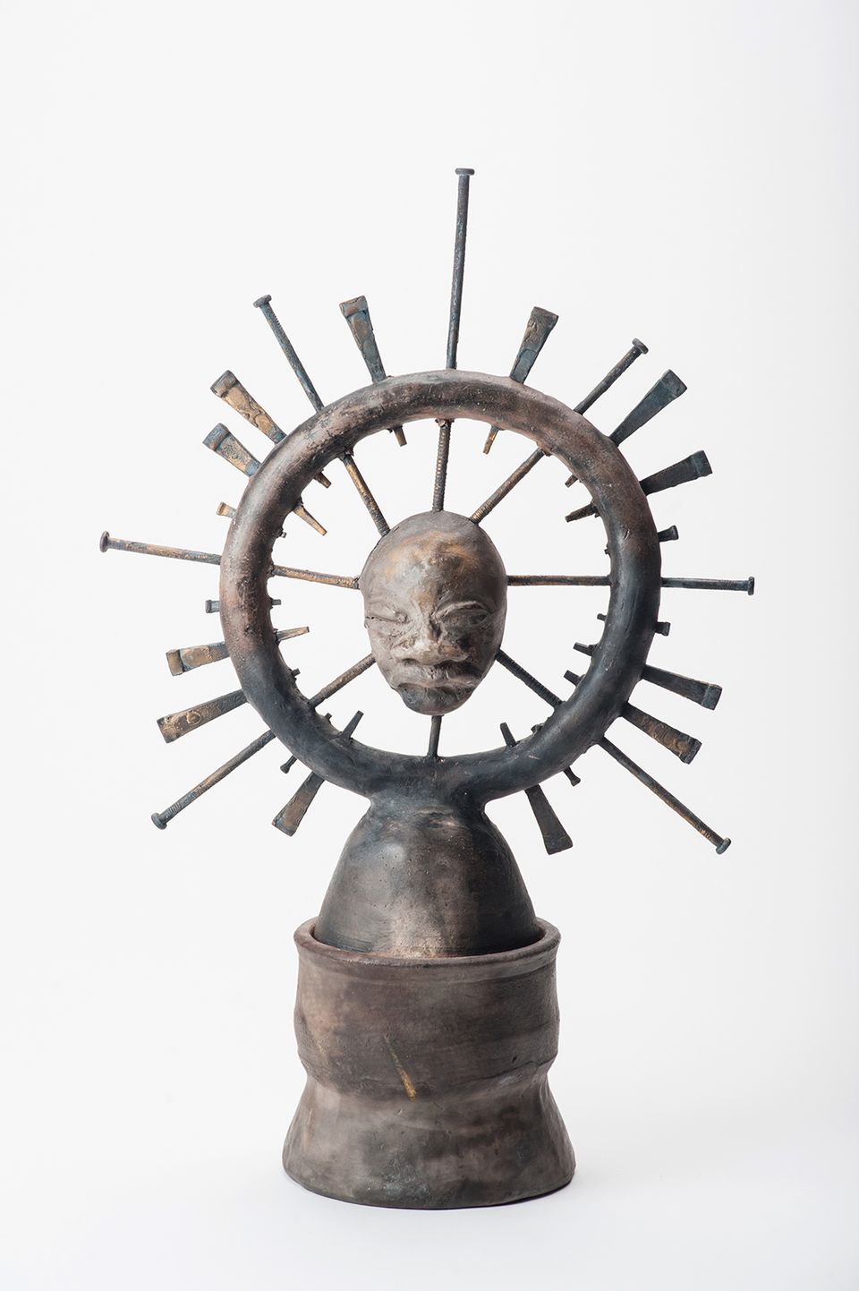 An image of a sculpture with a circle and nails piercing the top of it.