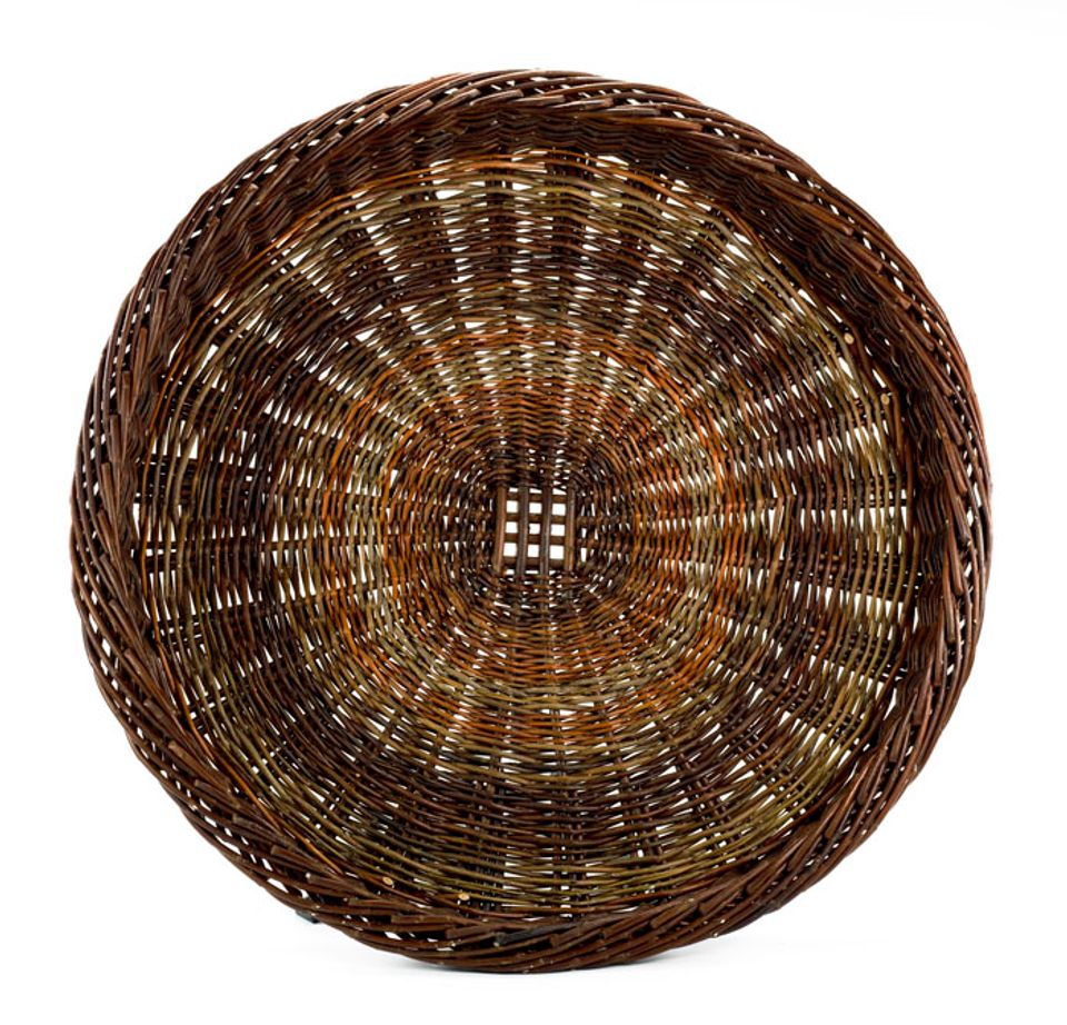 A basket that is the shape of a large plate with a multicolored design.
