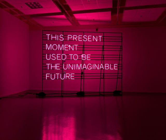 A pink neon sign that reads "This Present Moment Used to be the Unimaginable future