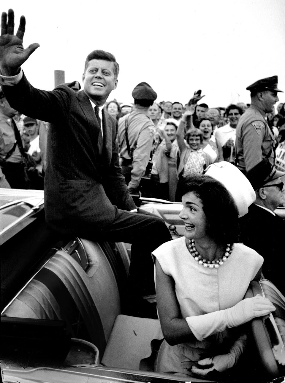 A photograph of President Kennedy waving to the crowd in his car from the exhibition American Visionary: John F. Kennedy's Life and Times