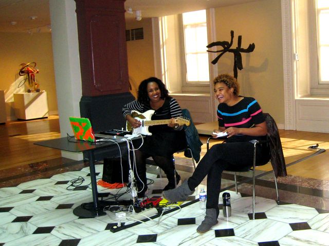 The two members of the band sit in the Luce Foundation Center with an electric guitar and audio equipment