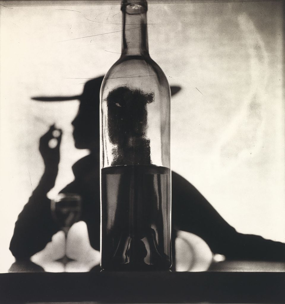 A photograph through a glass bottle of a black silhouette. 