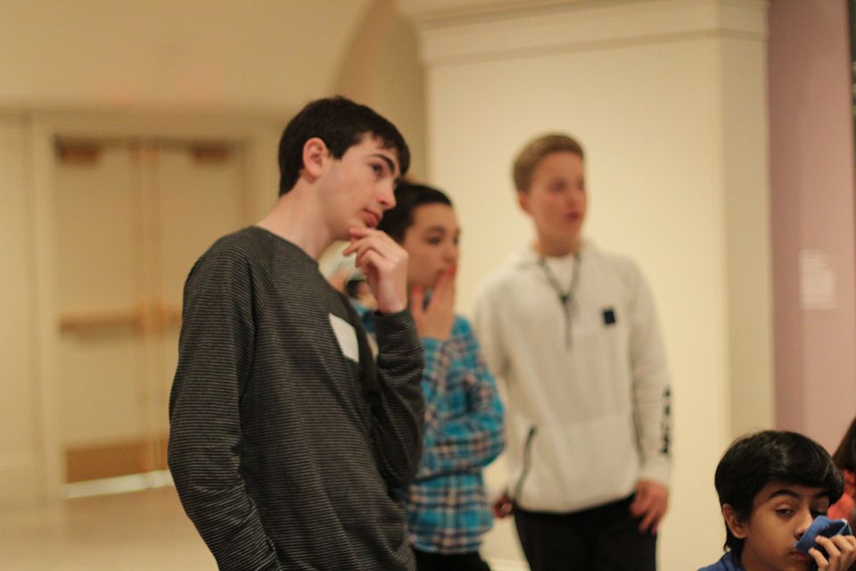 A group of teens looking and pondering at something. 
