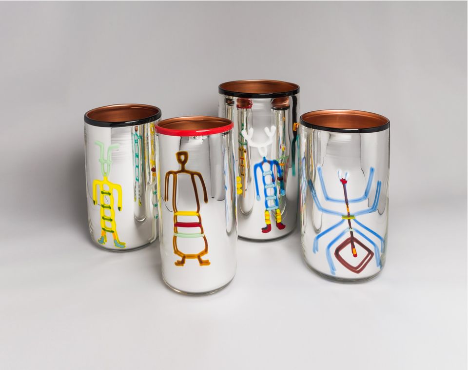 Four mirrored cups with stylized motifs on the front.