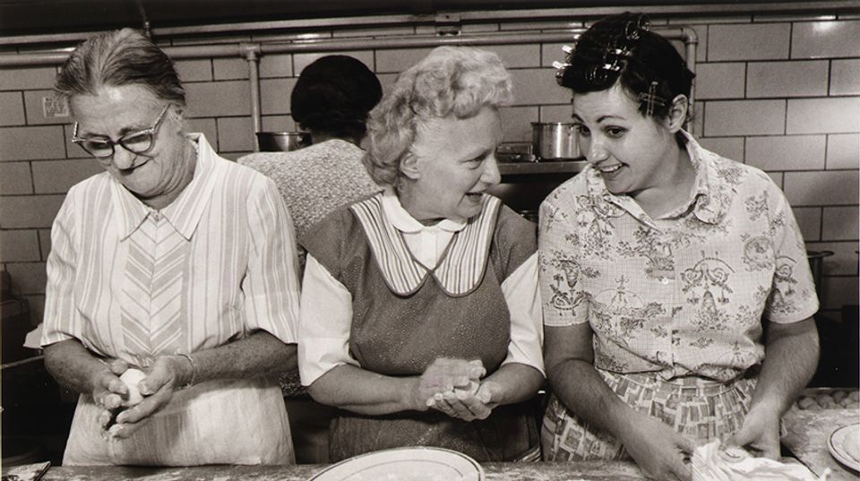 Three women sitting side-by-side preparing food