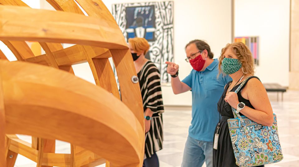 A photograph of people inside an art gallery with masks on.