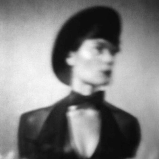 An evocative black and white photo of performer Jax Deluca in bowtie, hat, and tux.