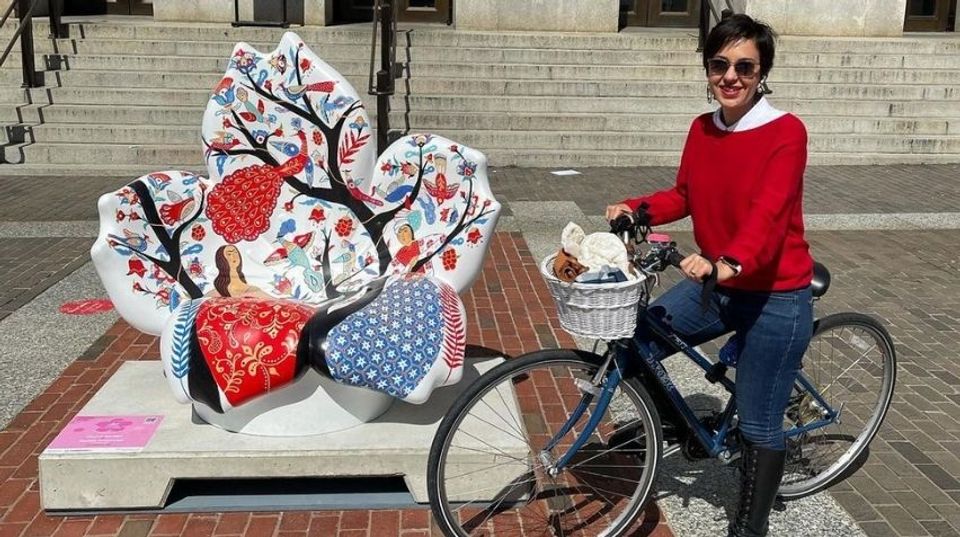 Rashin Kheiriyeh on her bike next to her cherry blossom sculpture
