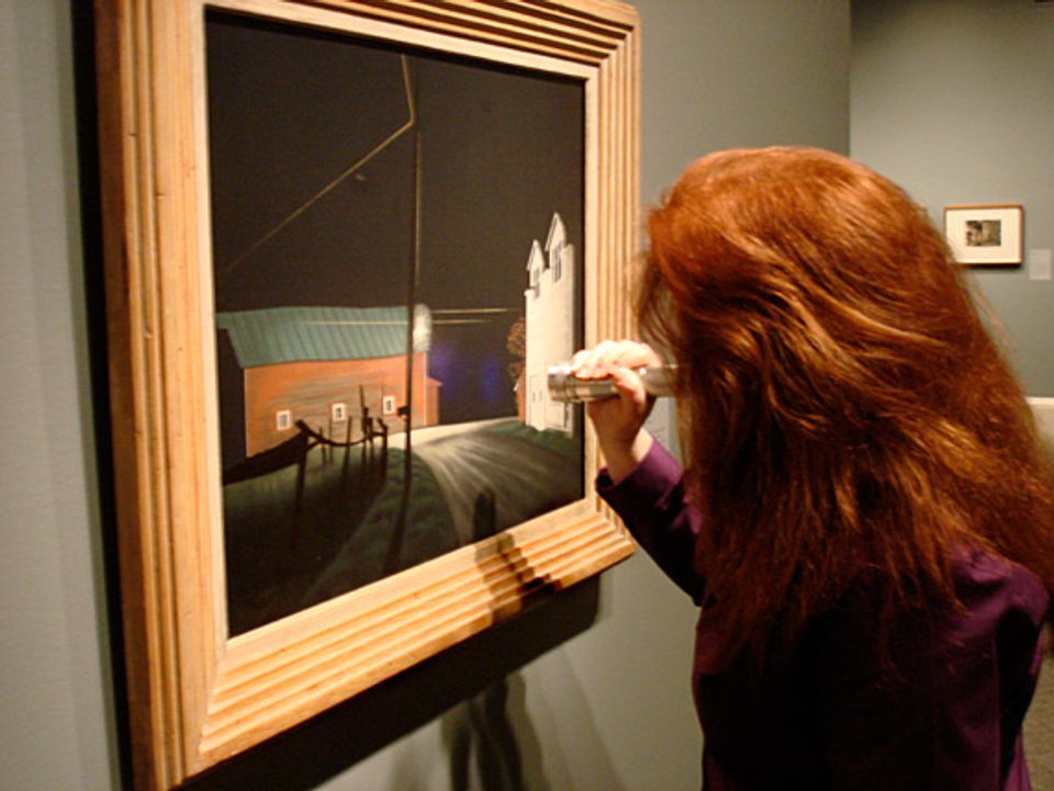 Paintings Conservator, Amber Kerr-Allison does a final inspection of George Ault's painting Bright Light at Russell's Corners with a UV flashlight just before the show opens.