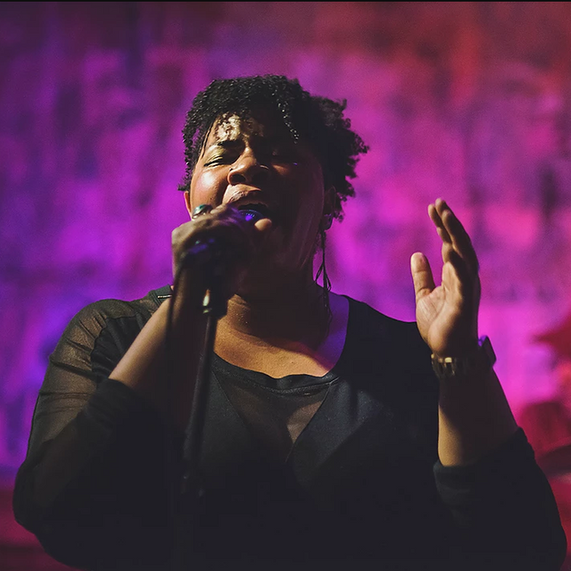 Picture of a woman singing, against a purple background.