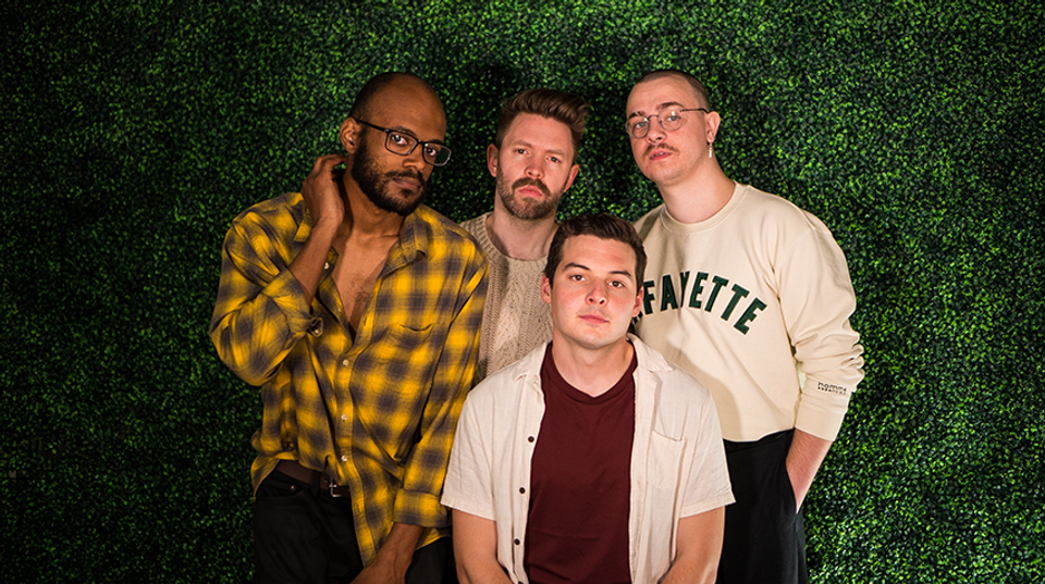 The four members of Broke Royals stand in front of a leafy green background.