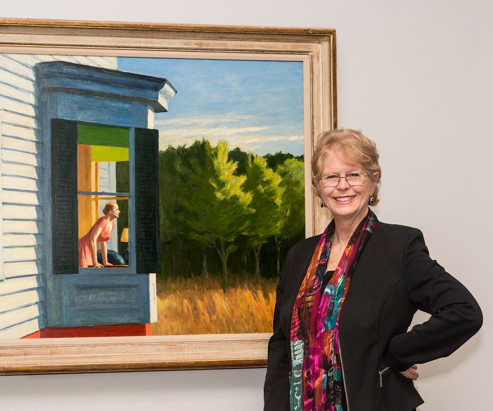 A photograph of Virginia Mechlenburg in front of an Edward Hopper painting.
