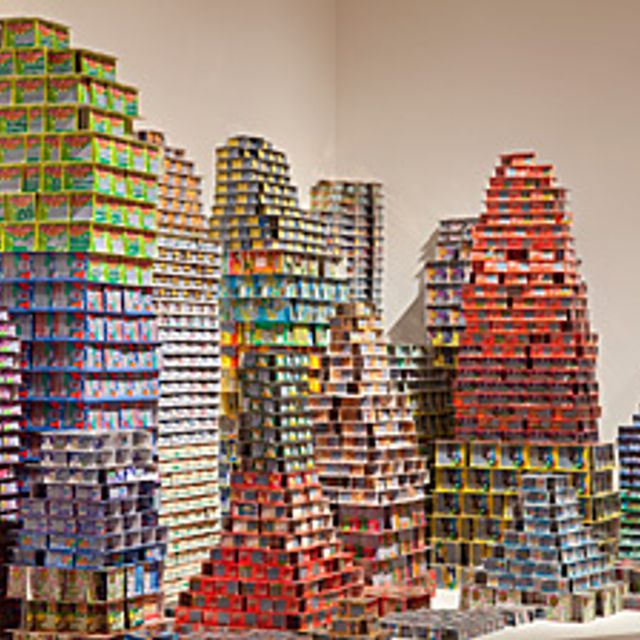 An installation of scratch & win lottery tickets stacked on top of one another forming structures. 