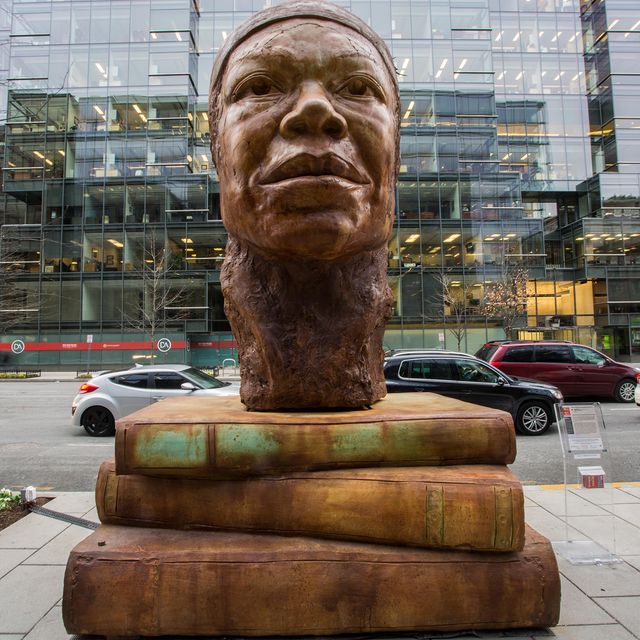An image of a large scale sculpture with the head of Maya Angelou resting on books.