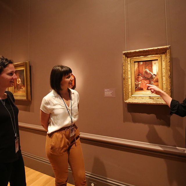 a photograph of four individuals looking at a work of art in a museum.
