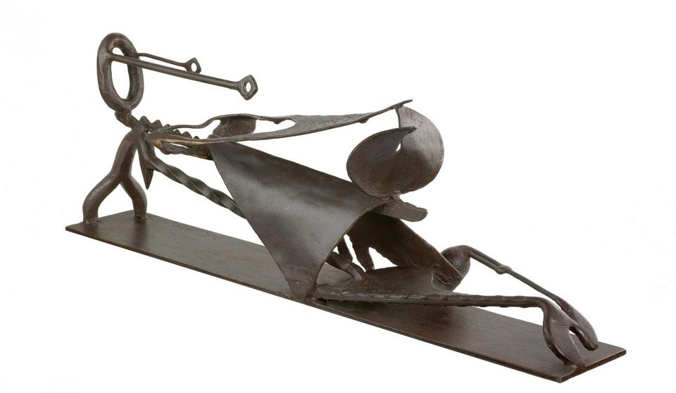 An iron sculpture of a figure reclining. 