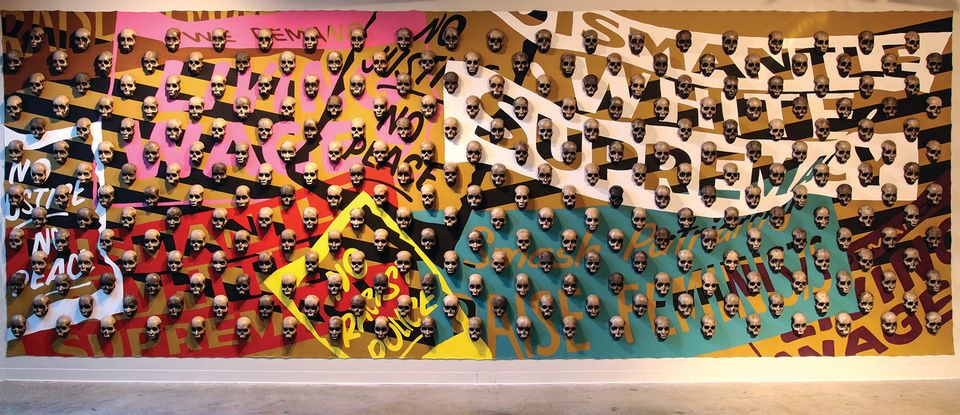 An image of an installation on a wall with skulls and many background colors.