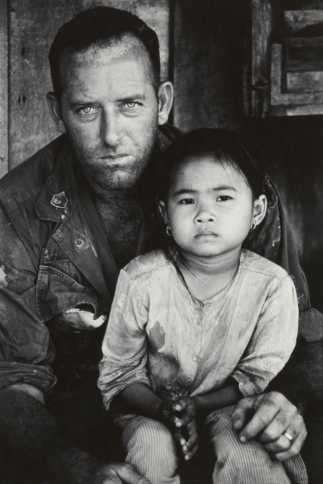 A photograph of a man holding a child in his lap.