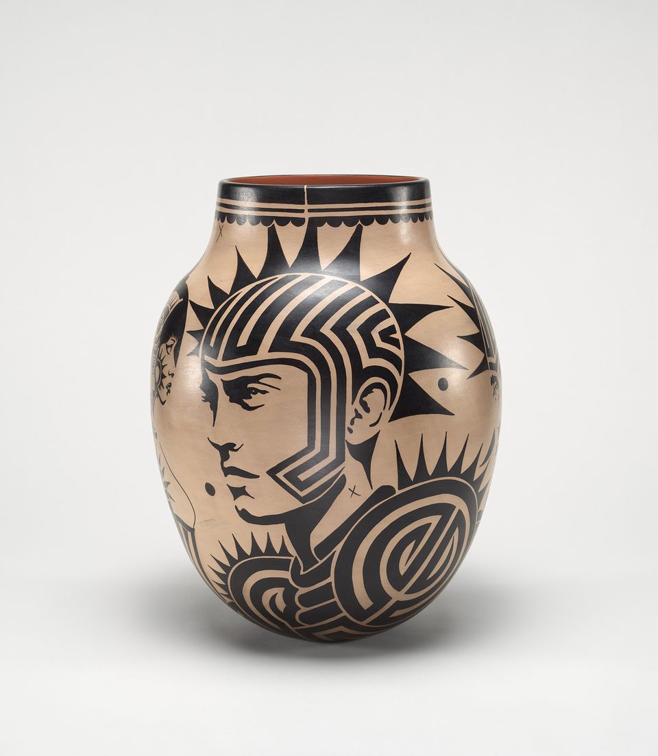 Decorative tan vase featuring stylized black line portraits and abstract geometric designs, set against a neutral white background.