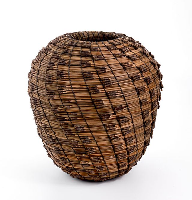 A basket that is long with a small top and bottom that flares out in the middle.