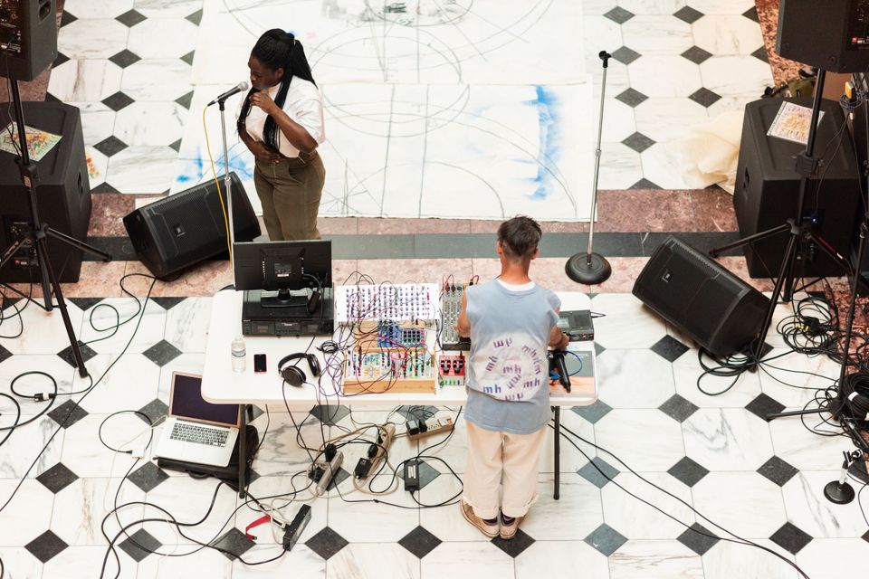 A woman sings in front of a synth player in the Luce Center