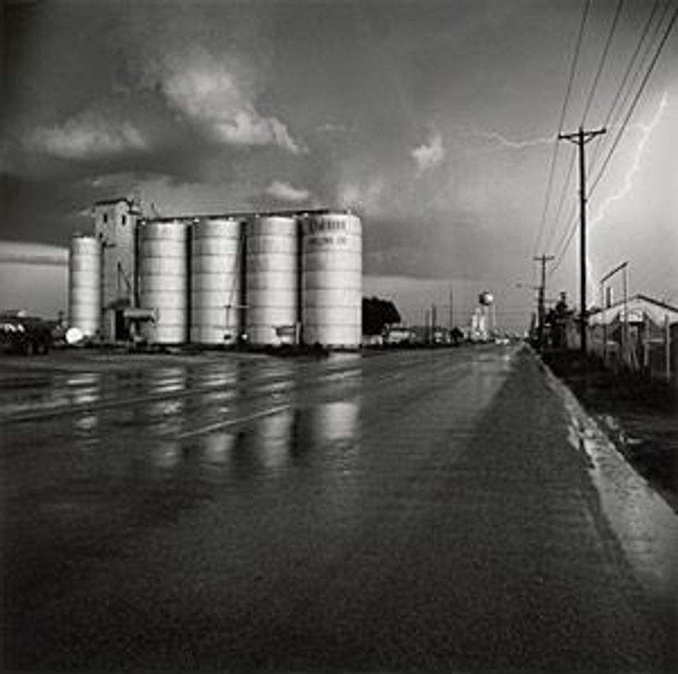A photograph of a grain elevator in a lightning storm.