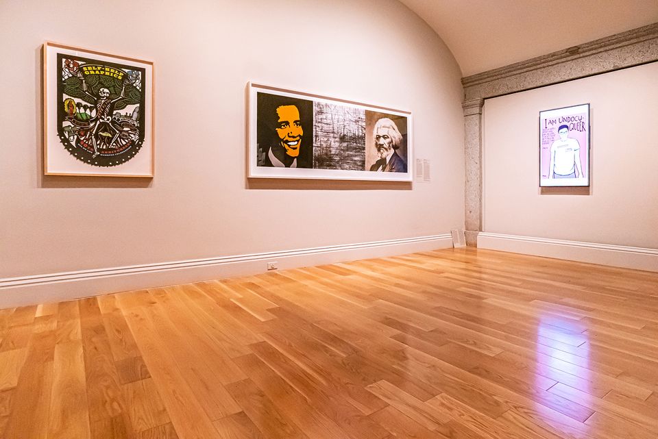 A photograph with artwork on the wall inside a gallery. 