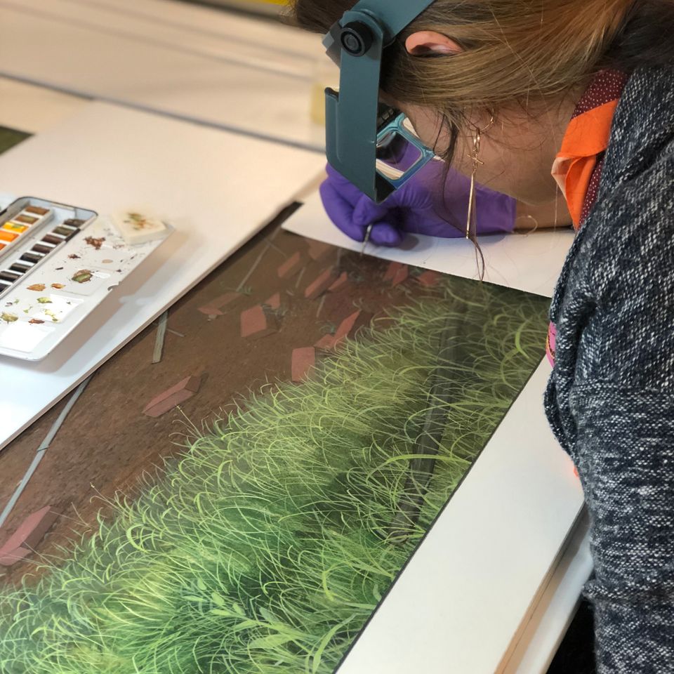 A photograph of a conservator looking over a painting and touching it up. 