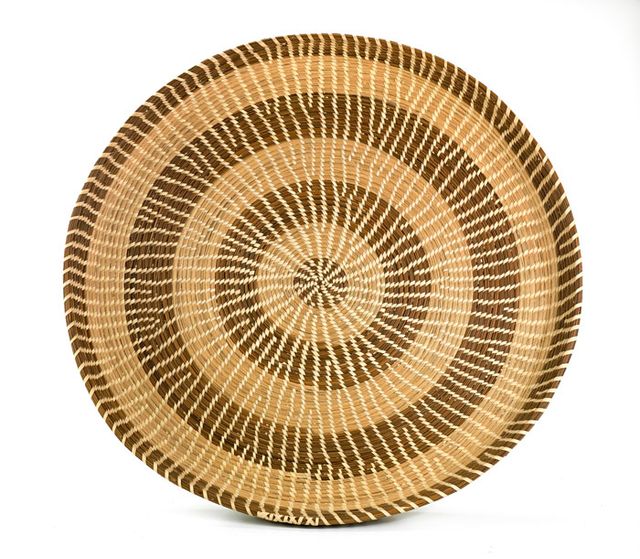 A basket that's circular and flat like a plate with two different colors.