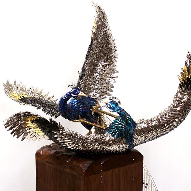 A photograph of a three dimensional artwork of two birds fighting.