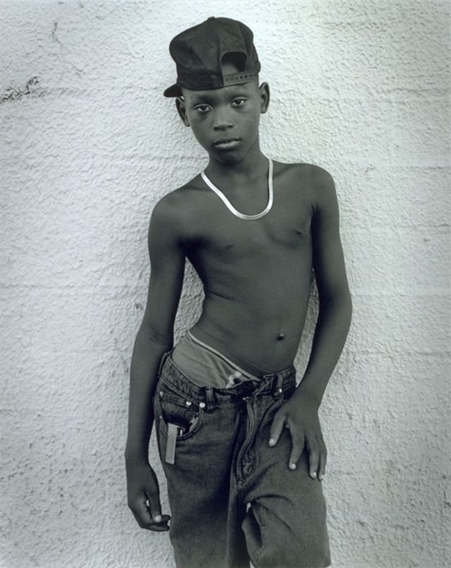 Hudnall's gelatin silver print of a young boy posing on a wall.