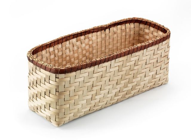 A basket that is long and rectangular with a dark trim and a light body.