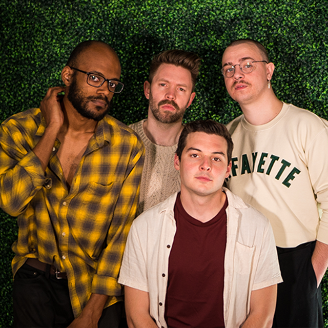 The four members of Broke Royals stand in front of a leafy green background.