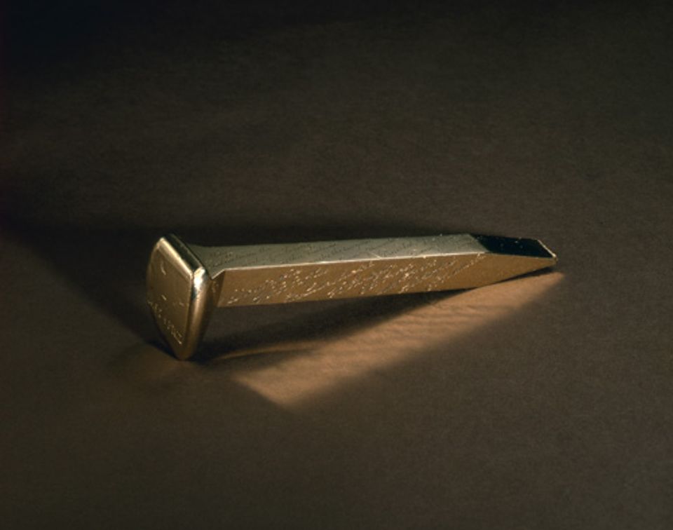 An image of a gold and copper railroad spike. 