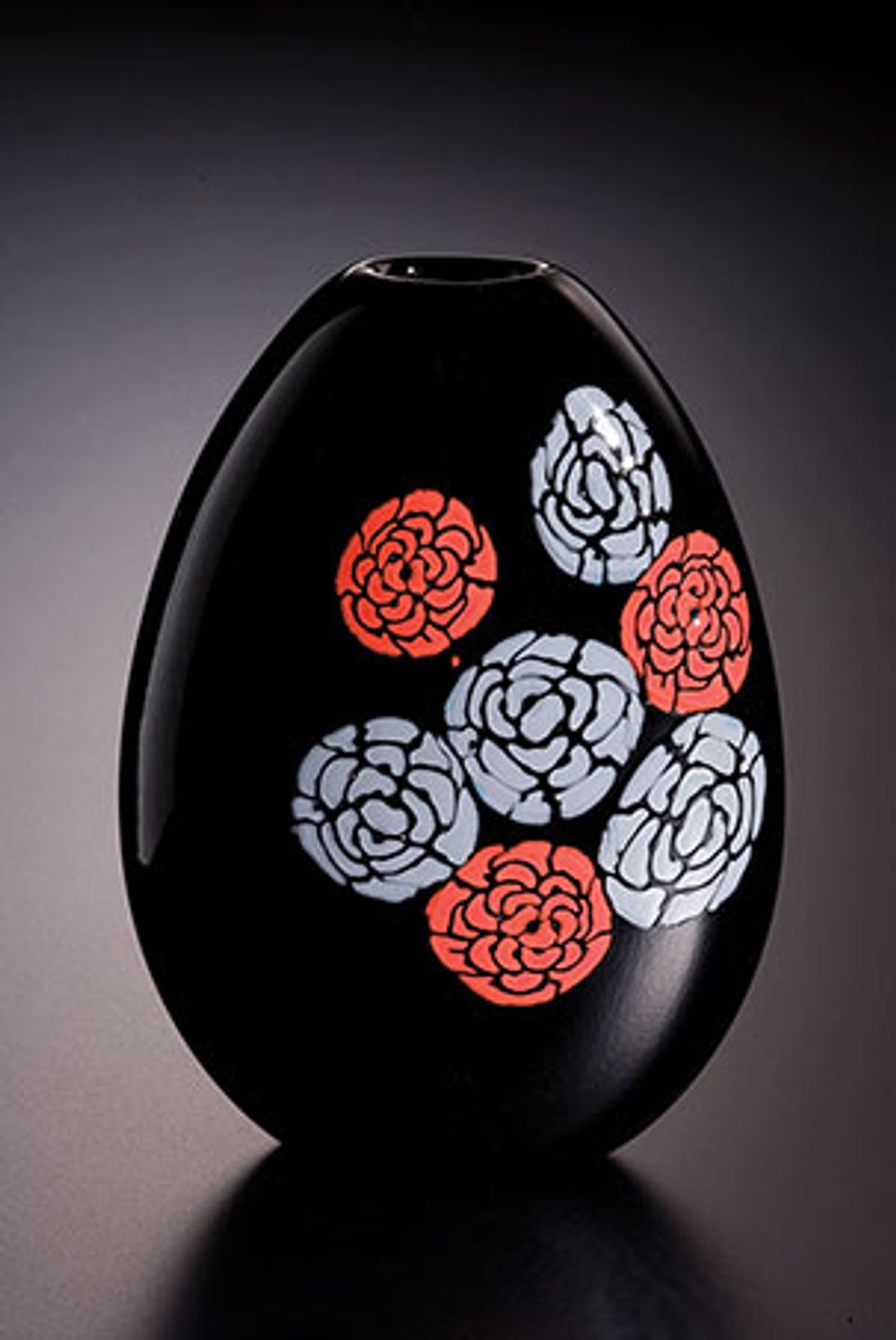 A black glass vessel with red and white flowers.