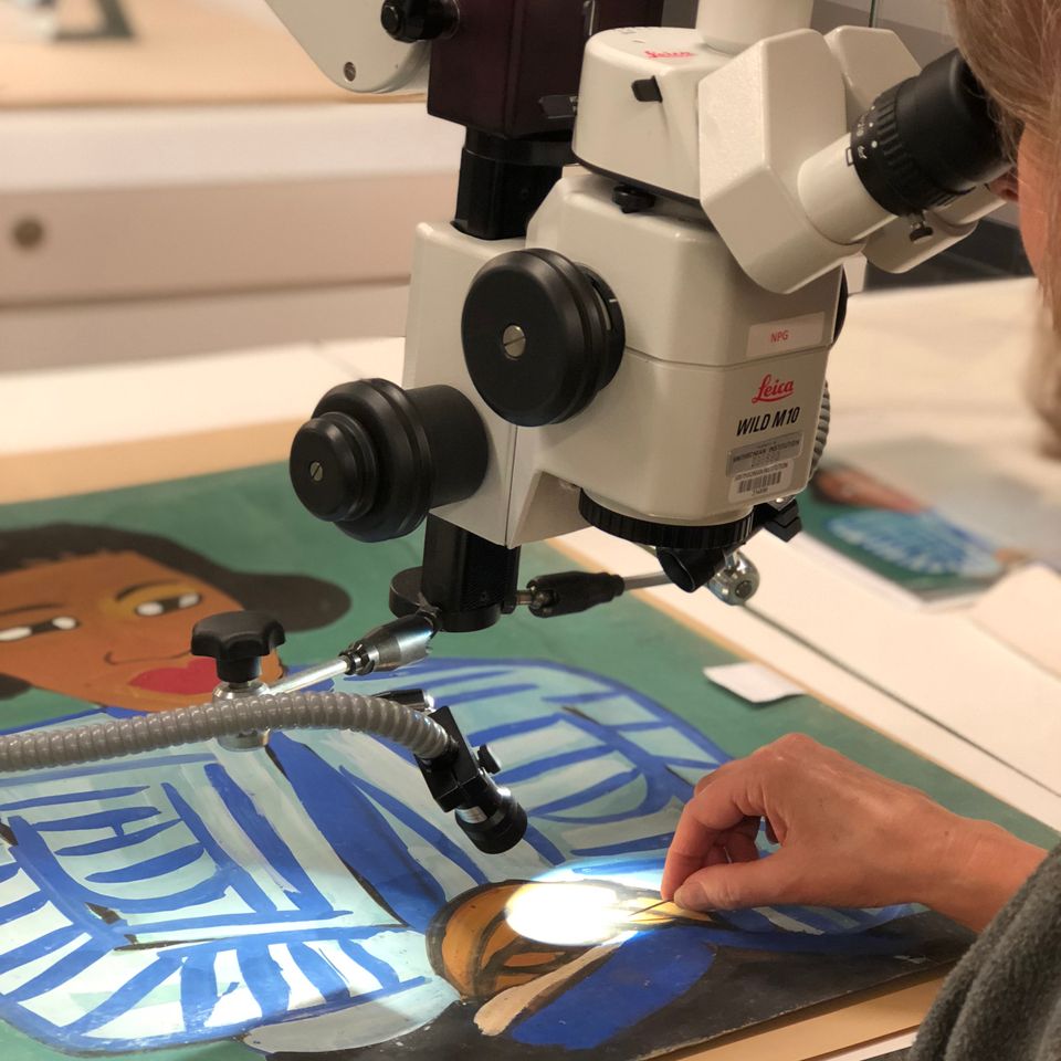 A photograph of a conservator looking at a painting under microscope. 
