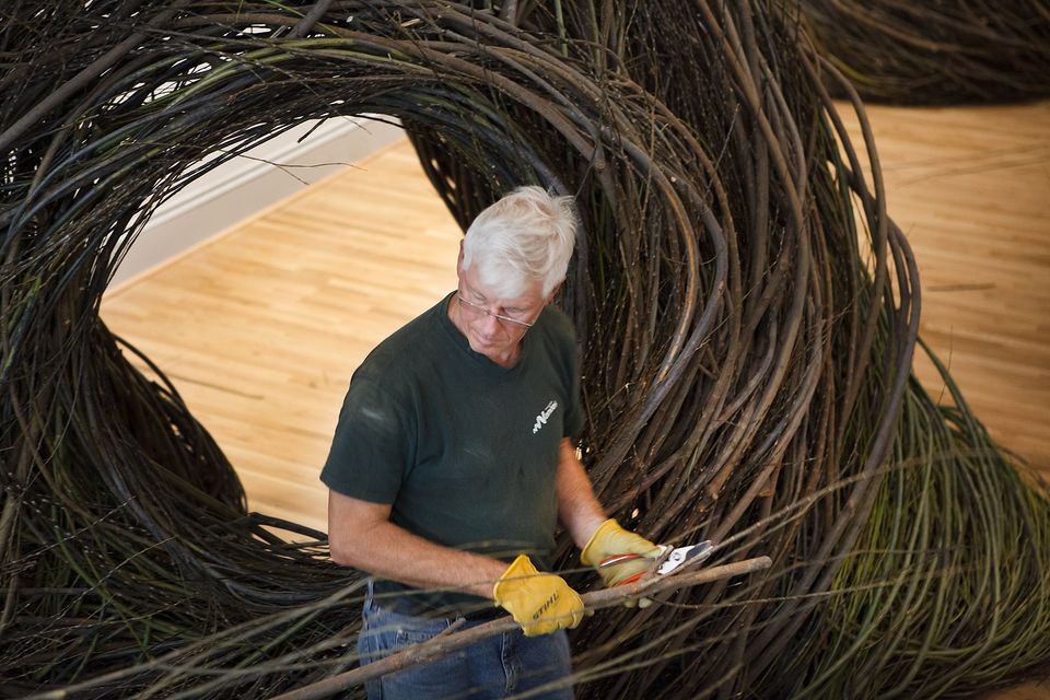 A photograph of a man working to mold wood into a circular form.