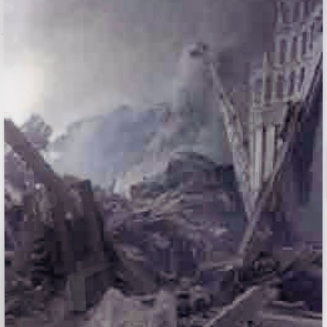 A pixelated photograph of a scene of a destroyed city. The image is in shades of gray.