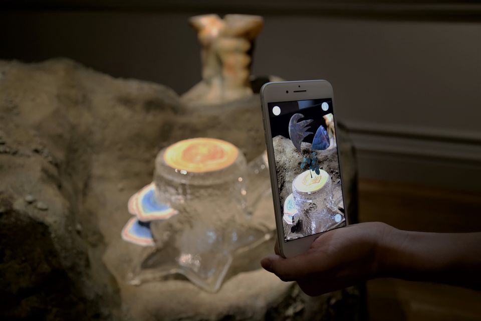 A photograph of a phone with an artwork digitally displayed on it.