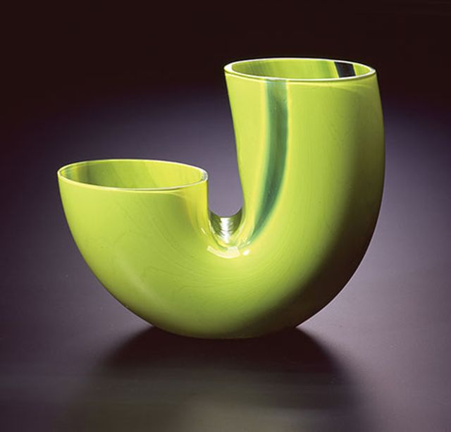 A glass vessel in green shaped as the letter 'J'