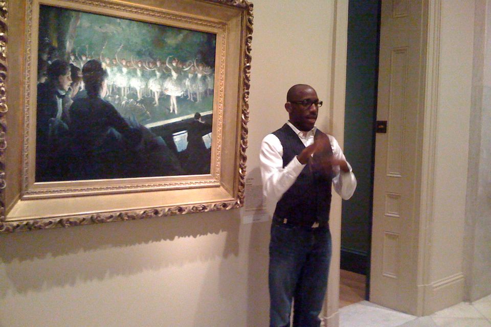 An ASL Interpreter interprets in front of a painting