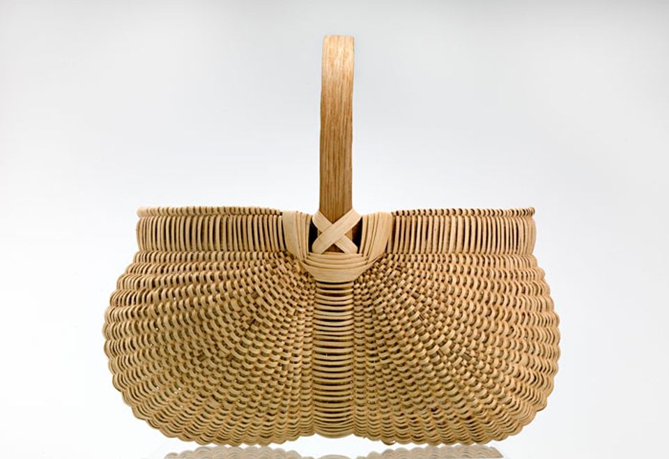 A basket with two circular sides that come together in the middle and are connected to a handle.
