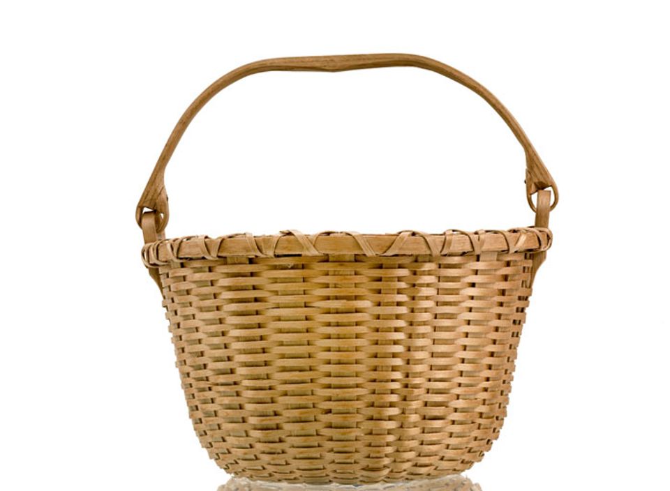 A small basket that's circular with a handle that goes across the body of the basket.