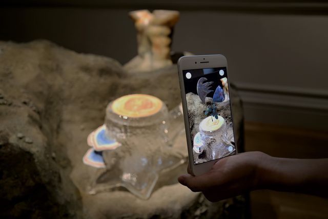 A photograph of a phone with an artwork digitally displayed on it.